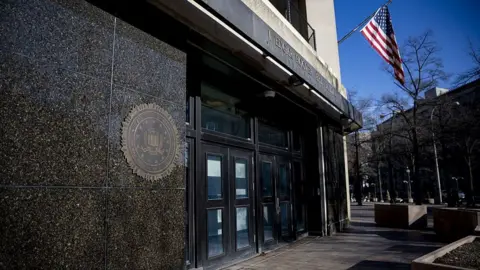Anadolu via Getty Images Close-up of the entrance of the FBI headquarters, with the US flag flying above it, in Washington DC