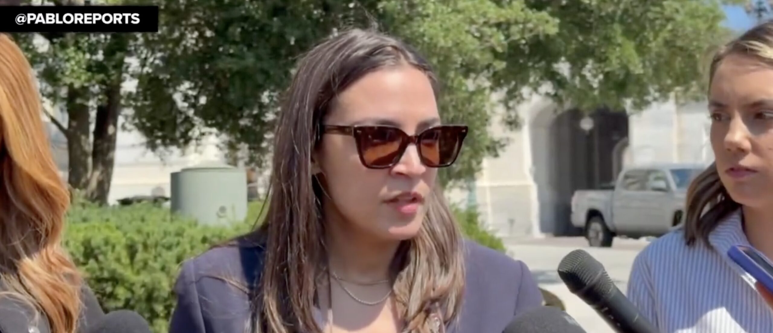 Aoc with sunglasses on speaks to the press outside