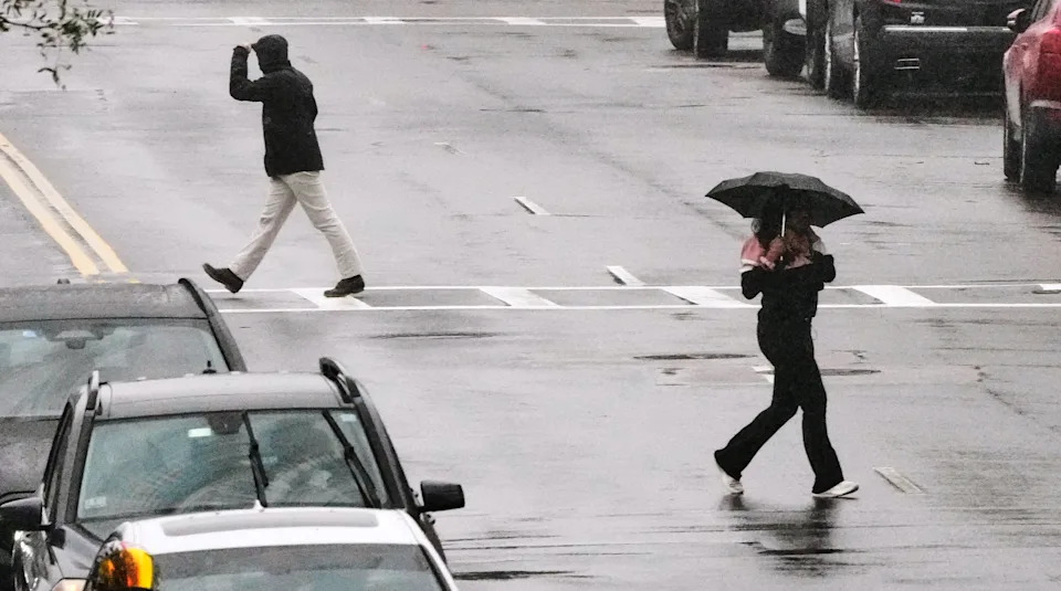 Pedestrians cross Broadway during a rain storm in the South Boston neighborhood during a nor'easter, Saturday, Sept. 26, 2026, in Boston. (AP Photo/Charles Krupa)