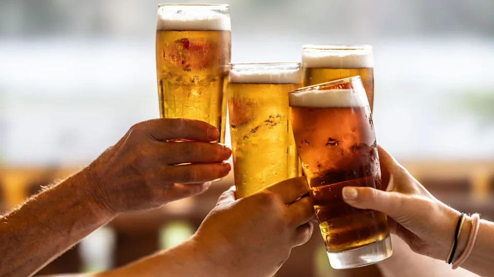 A group of people press their pint glasses together