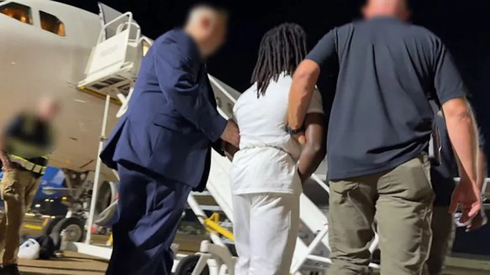 Haitian illegal immigrant Wisteguens Jean Quely Charles is escorted by federal agents to a plane. Charles was deported by ICE.