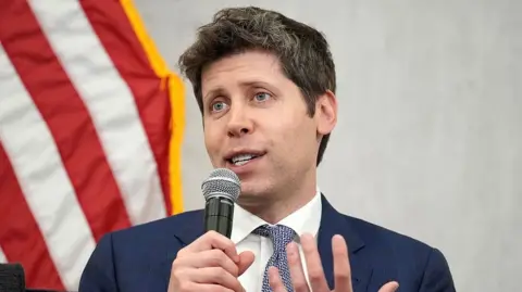 Getty Images Sam Altman, CEO of OpenAI, speaks to an audience. He is seated in front of the American flag.