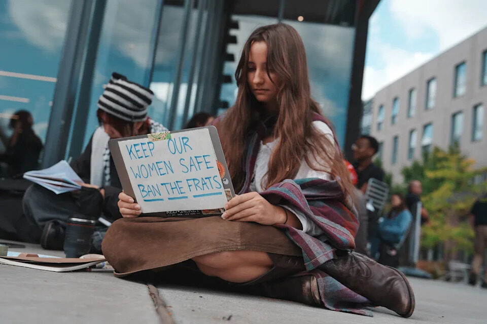 A Cornell University student sits with a sign during a campus-wide sit-in on Oct. 7.
