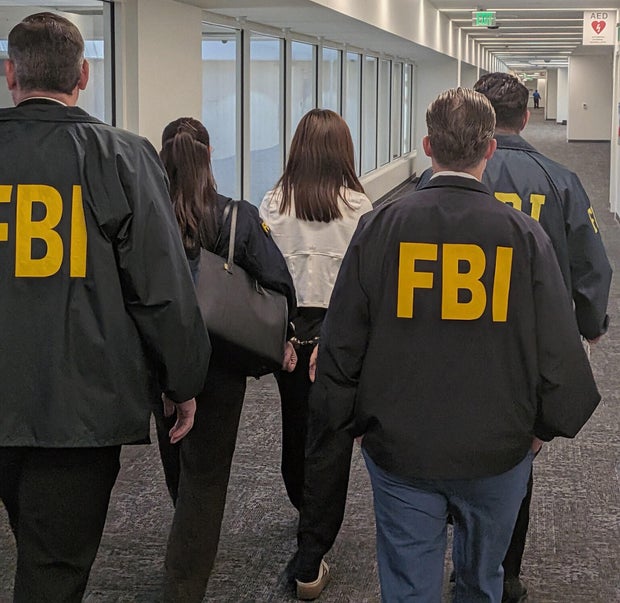 FBI agents walk with Wanying "Heather" Zhang in handcuffs after her arrest
